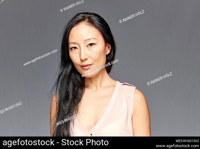 Portrait of woman with long black hair in front of grey background