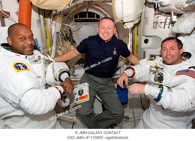 In the Quest airlock, astronaut Barry E. Wilmore (center), STS-129 pilot, assists crewmates Robert L. Satcher Jr. (left) and Mike Foreman, mission specialists