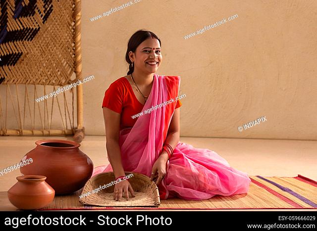 A rural woman grinning with a sieve