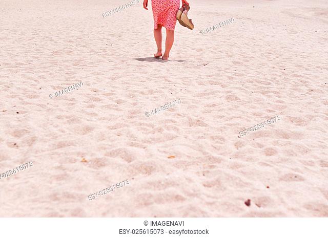 Back shot of the woman walking on the sandy beach