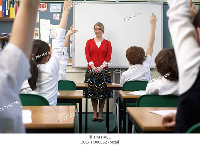 Children raising hands in classroom