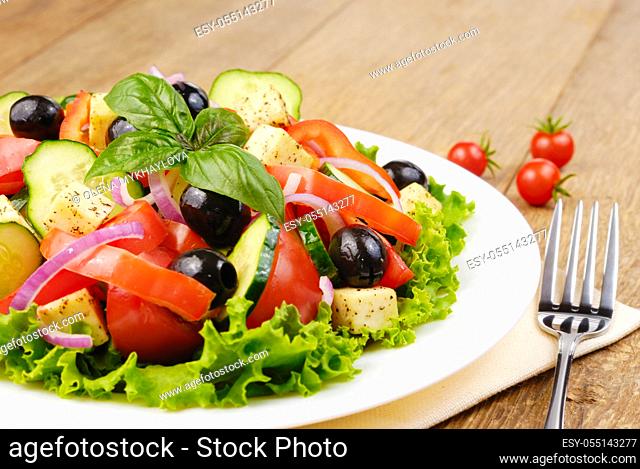 Greek salad in the white plate on the kitchen table