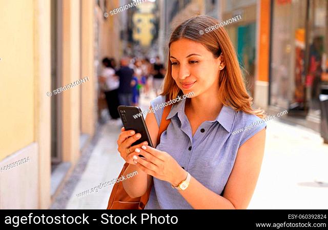 Happy young woman in city street using a mobile phone