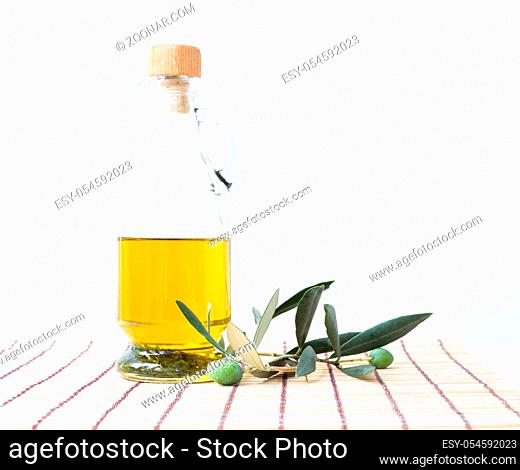 Glass bottle of olive oil and some olives with leaves isolated on a white background