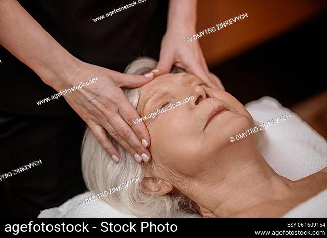 Face massage. A senior woman having a face massage in a beauty salon