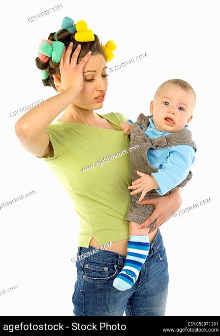 Young, depressed woman with baby on hands. Woman is holding her's head. Baby is looking at camera. White background, front view
