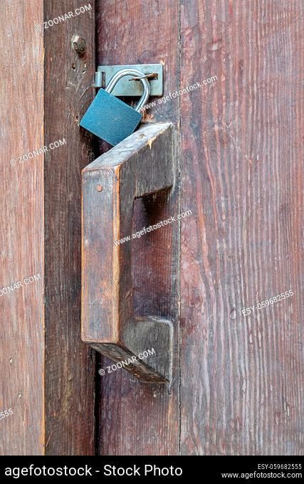 Closeup of a wooden aged latch locked with a padlock in a wooden door