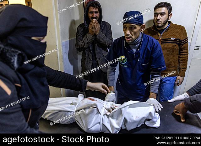 09 December 2023, Syria, Idlib: A man cries near the body of his dead child, who was killed in missile strikes targeted the city of Idlib, at SAMS Hospital