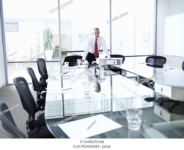 Businessman alone in a boardroom leaning on table
