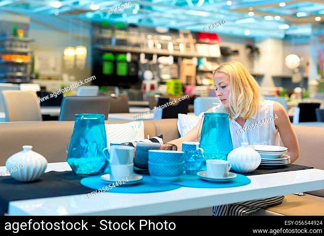 Pretty, young woman choosing the right item for her apartment in a modern home decoration furnishings store