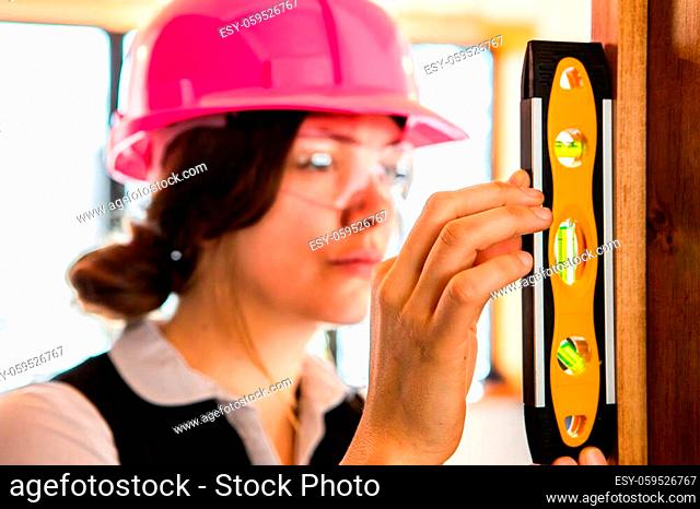 selective focus and close up view of spirit level on woman's hand, her attractive face in the background. female construction inspector at inspection