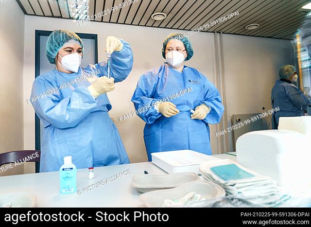 25 February 2021, Rhineland-Palatinate, Mainz: A pharmacist pulls up AstraZeneca vaccine and is observed doing so. Thousands of police employees in...