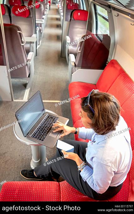 Business Woman Working on Laptop and Smartphone in First Class in a Train in Switzerland