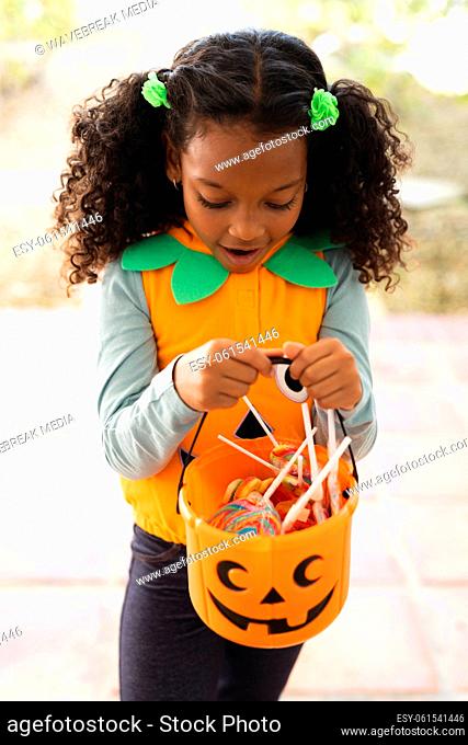 Vertical image of happy african american girl in halloween costume with basket