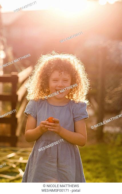 Portrait of little girl standing at backlight in the garden