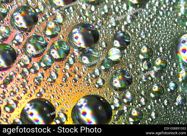 Close up view of many colorful and bright drops of water on a shiny surface