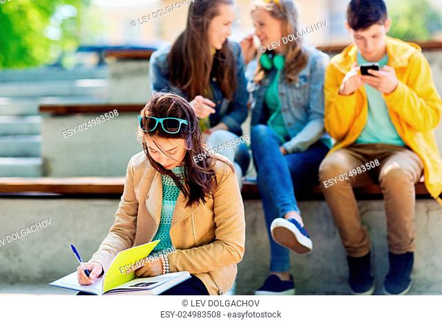 education, bullying, high school, social relations and people concept - unhappy student girl with book suffering of classmates mockery