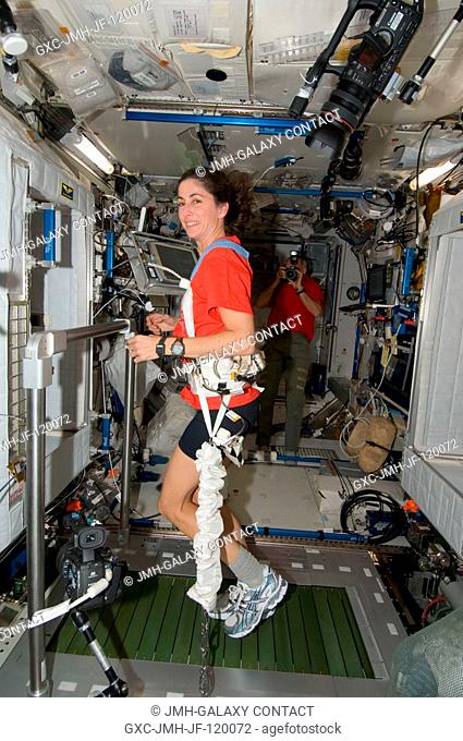 NASA astronaut Nicole Stott, Expedition 2021 flight engineer, equipped with a bungee harness, exercises on the Combined Operational Load Bearing External...