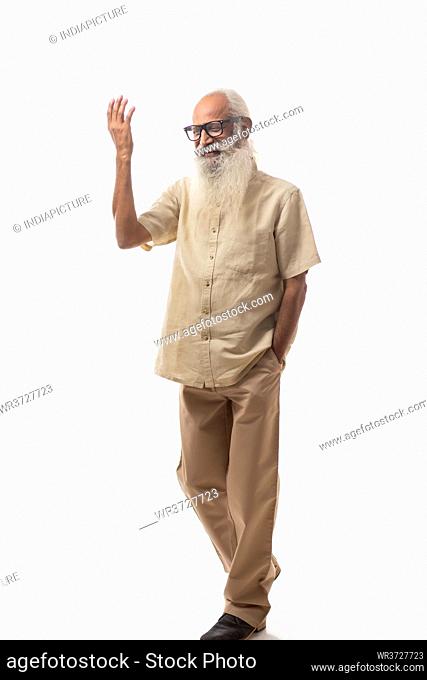 A CHEERFUL OLD MAN STANDING AND GESTURING WHILE TALKING