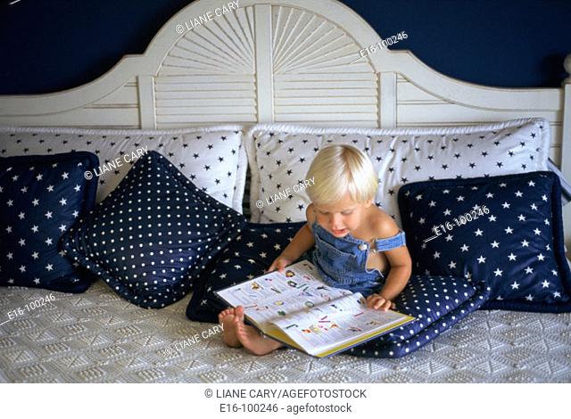 Young boy reading on bed