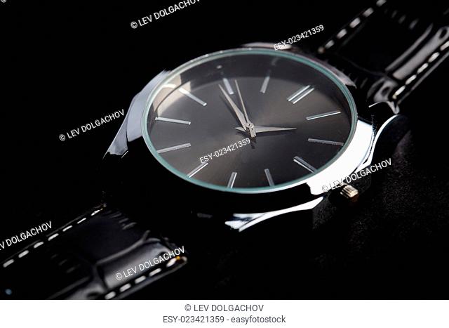 time, punctuality, object and accessory concept - close up of black classic male wristwatch