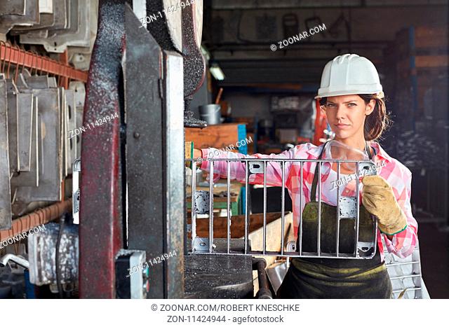 Frau als Metallbauer Lehrling mit einer Gussform im Lager einer Metallfabrik