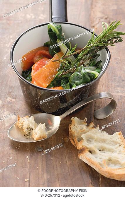 Vegetables with rosemary in a pan, toasted bread beside it