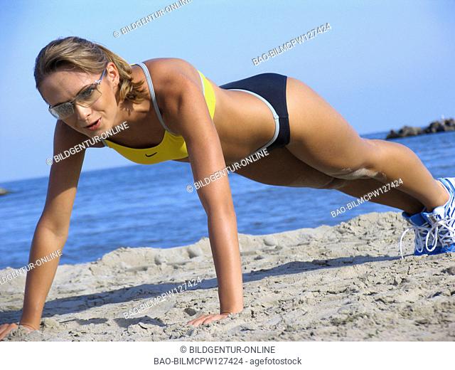 Woman does gymnastics on the beach