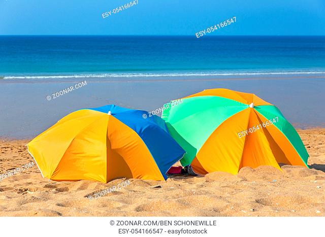 Two colorful beach umbrellas on beach by the sea