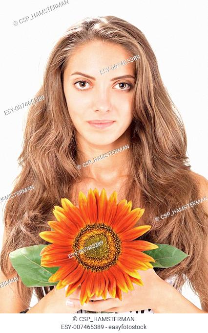 Young beautiful woman with long hairs holding sunflower near face