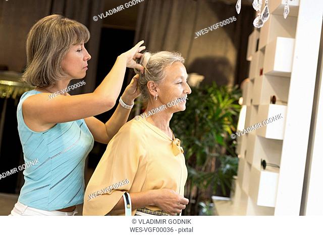 Woman helping senior woman with her hair in a shop
