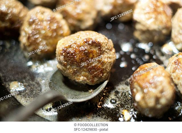 Meatballs being fried in a pan