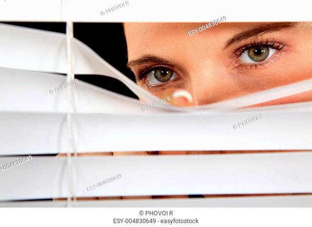 Woman peering through some blinds