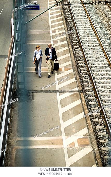 Businessman and businesswoman walking on railway platform