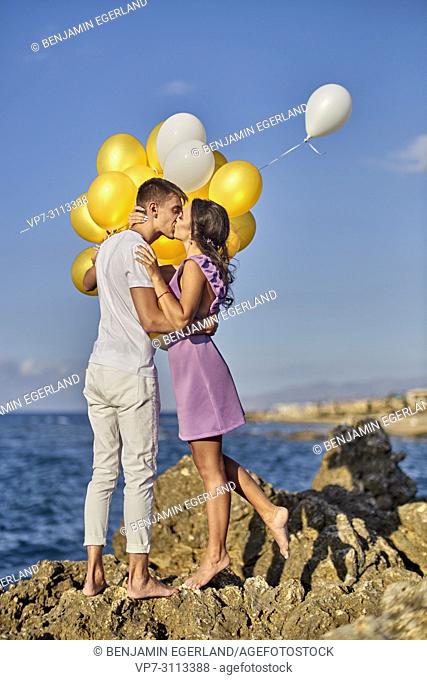 romantic couple kissing, balloons, seaside