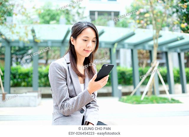 Businesswoman using smart phone in the park