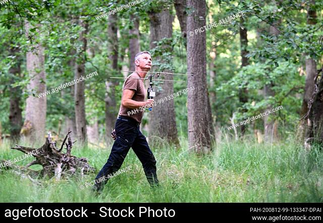 28 July 2020, Hessen, Mörfelden: Markus Dietz, biologist, walks through the forest with a tracking antenna. Some bats in the colony carry transmitters