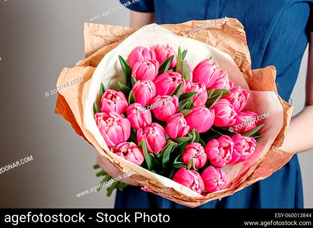 Florist girl with peony flowers or pink tulips Young woman with flower bouquet for birthday or mother's day