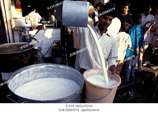 Street market scene with man pouring milk into bucket