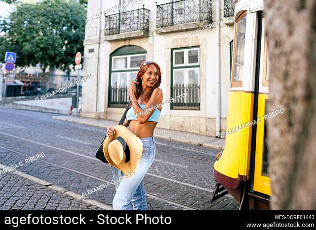 Happy young woman standing on road by cable car