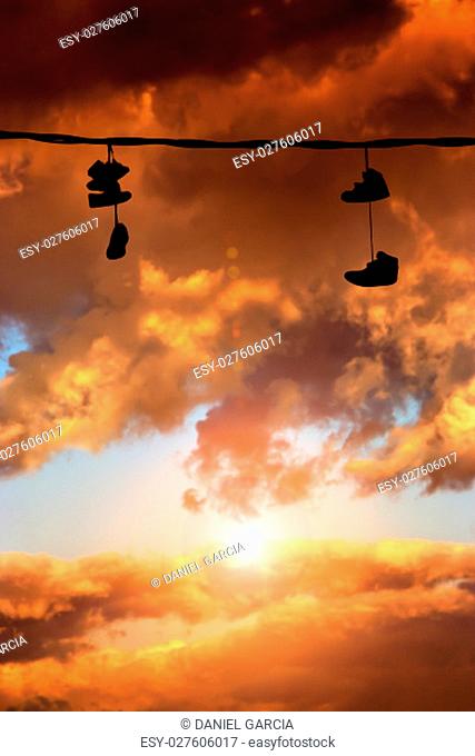 Several sneakers hung at sunset. Vertical image