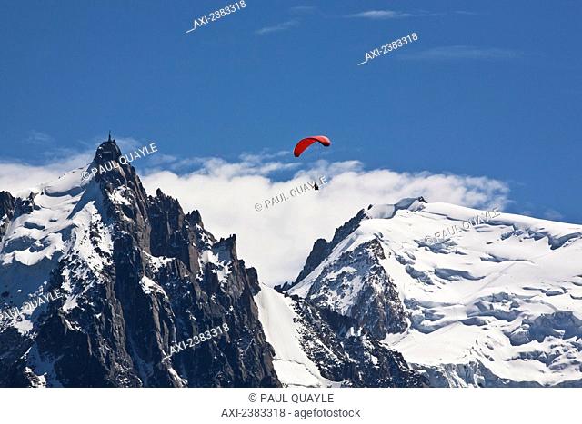 Paraglider above Chamonix-Mont Blanc valley, with Mont Blanc massif range mountain and Aiguille du Midi in background; France