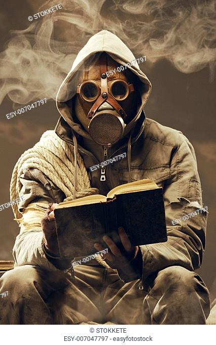 Post apocalyptic survivor in gas mask reading a book