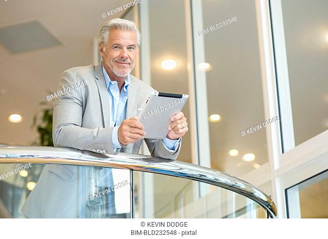 Caucasian man leaning on railing using digital tablet