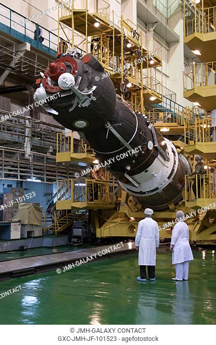 At the Integration Facility at the Baikonur Cosmodrome in Kazakhstan, technicians look on as the Soyuz TMA-06M spacecraft is lowered into place for insertion...