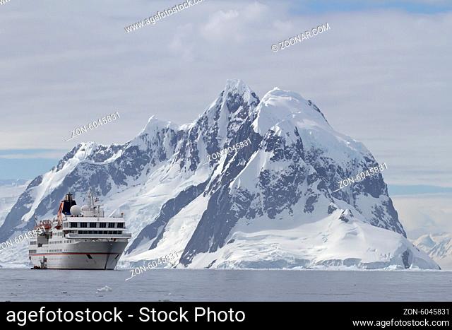 White tourist ship a summer day on a background of mountains of the Antarctic Peninsula