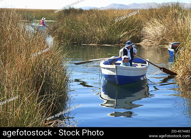 Aymara boy and girl on the boat between the islands made from reed in Uros Islands, Lake Titicaca, Puno, Peru, South America
