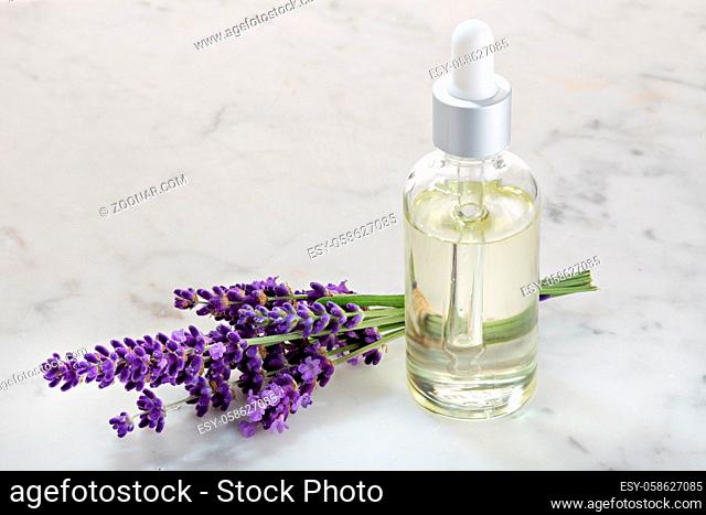 Lavender essential oil in glass bottle on marble table. Copy space