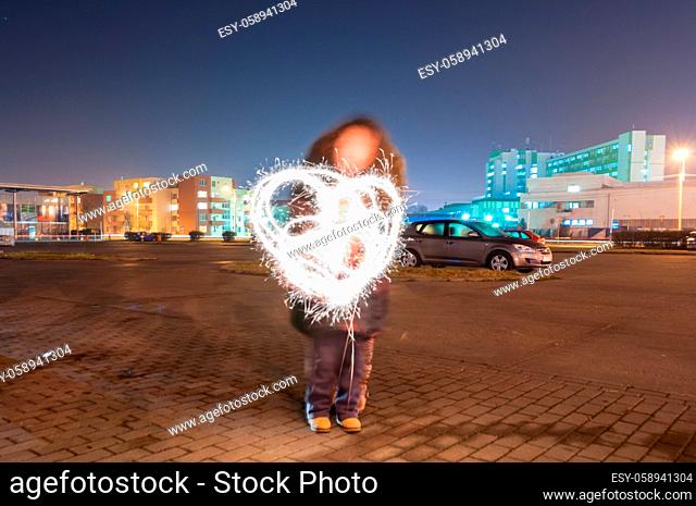 Mother and son drawing a heart with sparkle sticks. Light painting. Long exposure