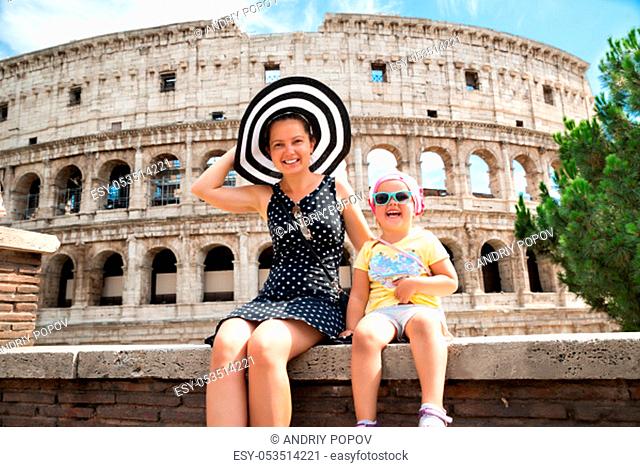 Young Mother And Daughter Sitting In Front Of Colosseum In Rome, Italy
